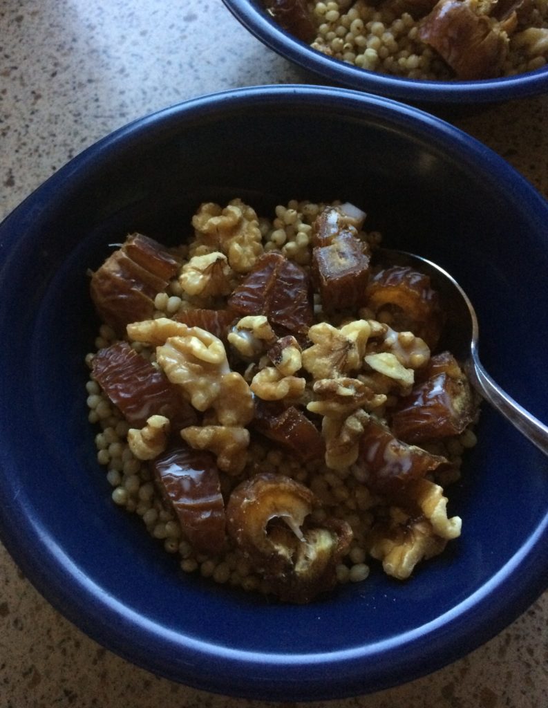 A bowl of hot cereal covered with chopped wlanuts and dates.