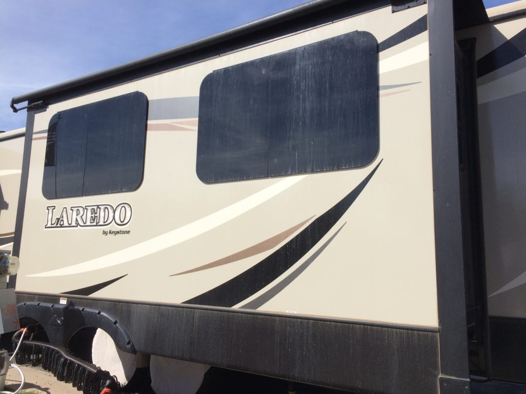 The side of an RV, streaked with dust.