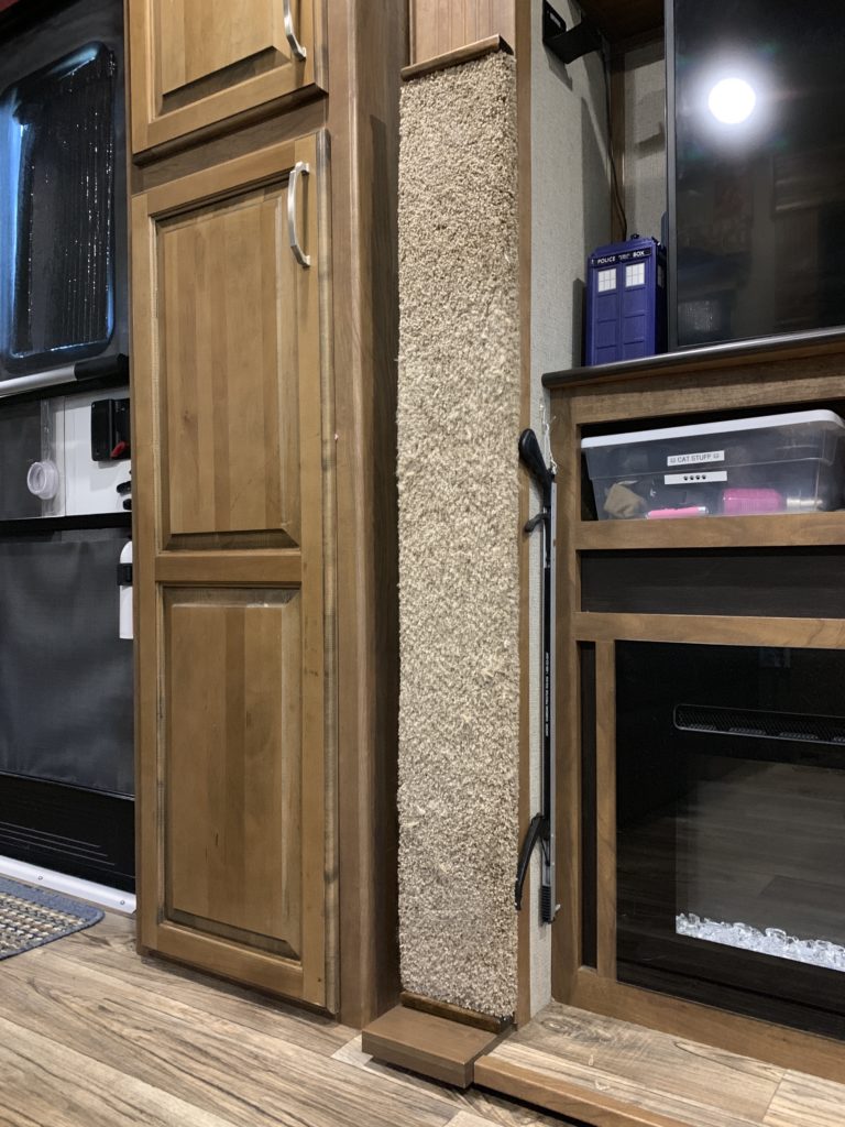 a carpeted scratcher along the length and width of the slideout trim, in between a small closet and a TV over a fireplace.