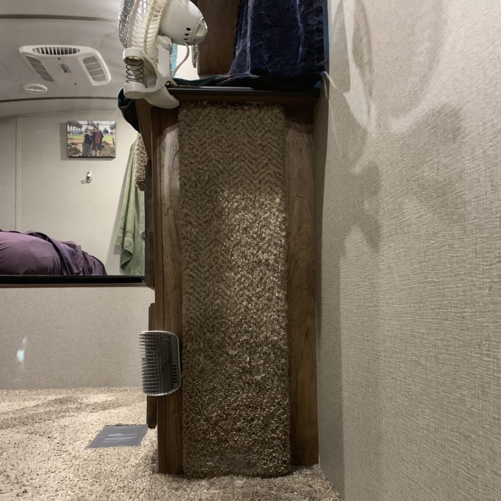 the side of an RV dresser attached to the wall, with the side covered in carpet for cat scratching.