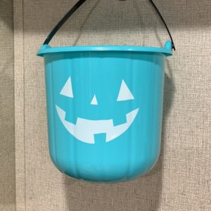 A teal pumpkin bucket hanging from a hook.