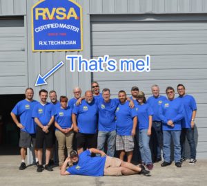 a group of adults wearing matching blue shirts under an RV Service Academy sign. An arrow points to one light skinned man with his hands on his hips and smiling, with the words Thats me!