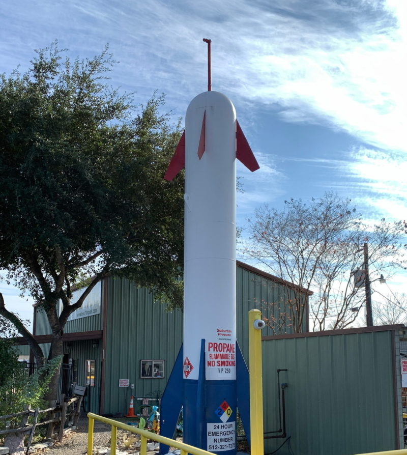 photo of a large tall propane storage tank thats been painted and adorned to look like a rocket.