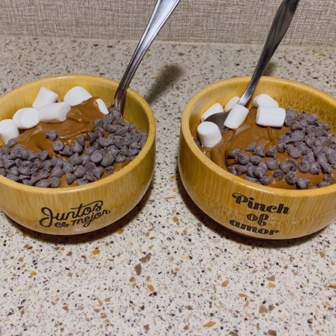 Two bamboo bowls with chocolate pudding, garnished with marshmallows and chocolate chips  