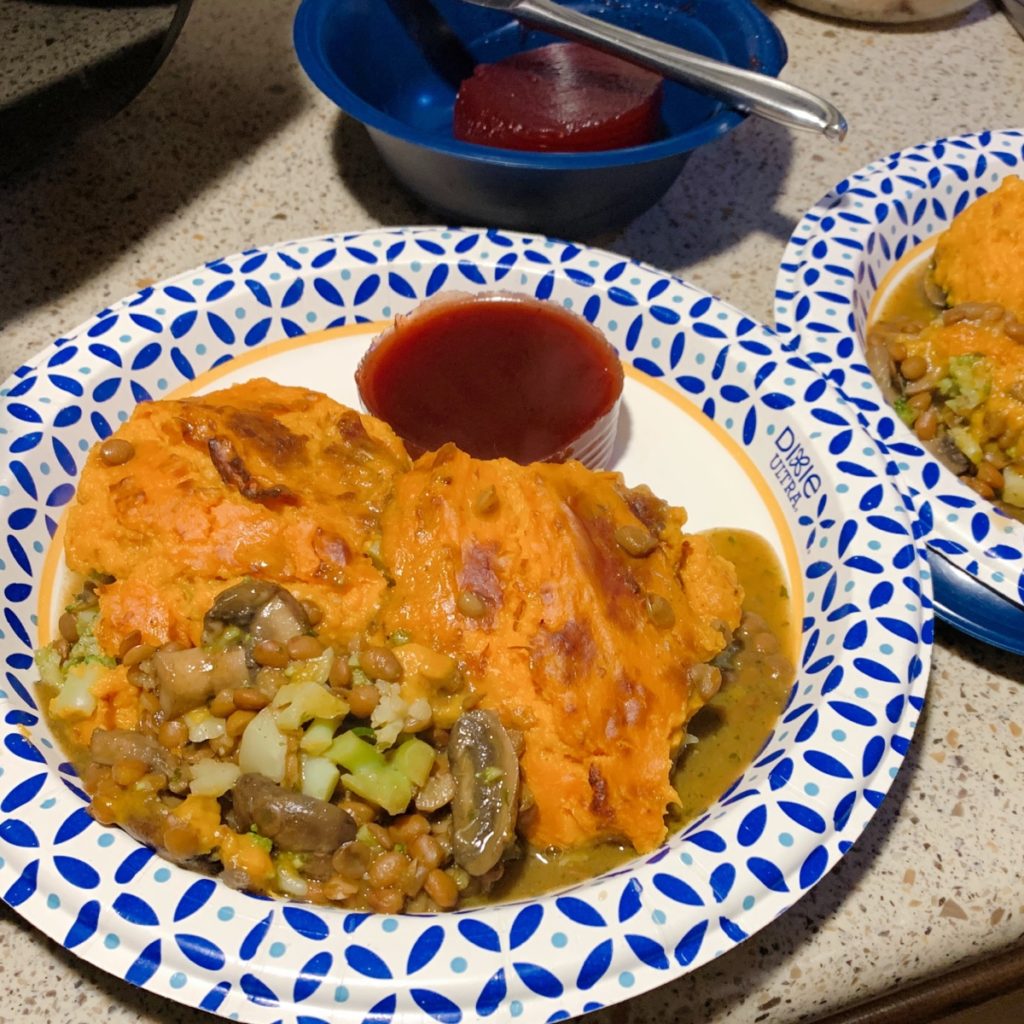 A plate of casserole with a slice of canned cranberry sauce  